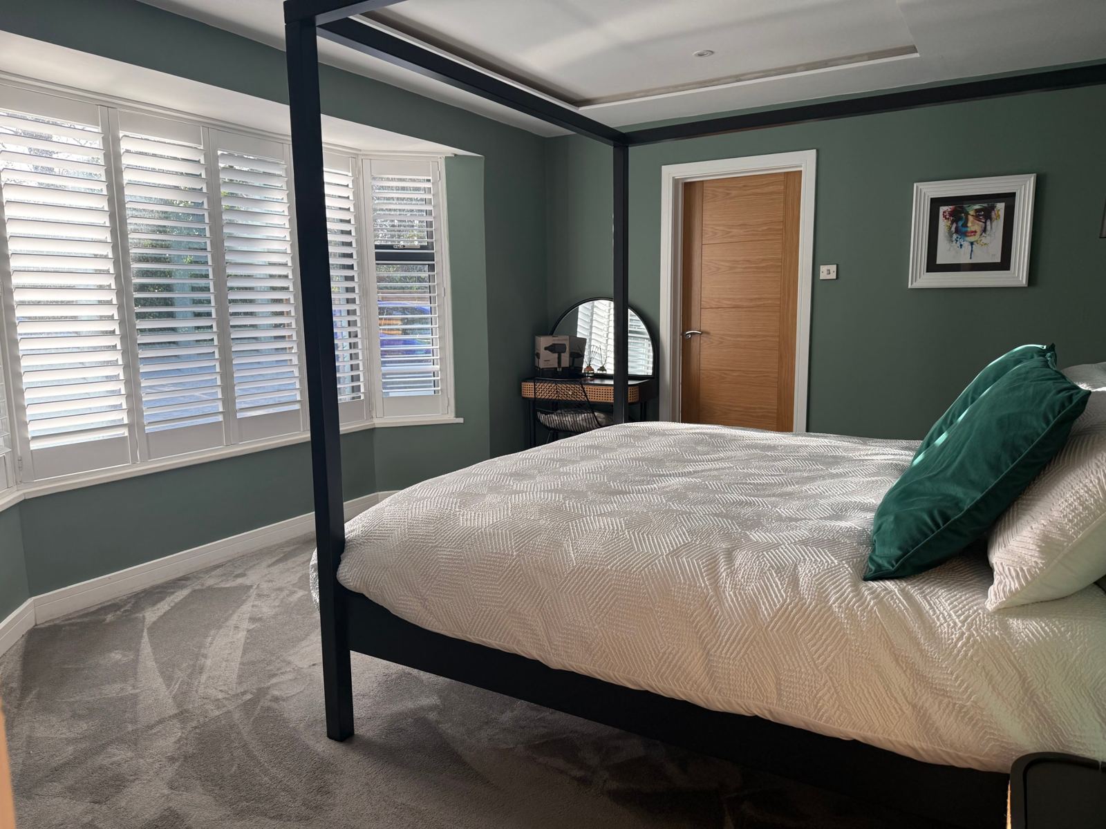 Master bedroom with a four-poster bed and plantation shutters