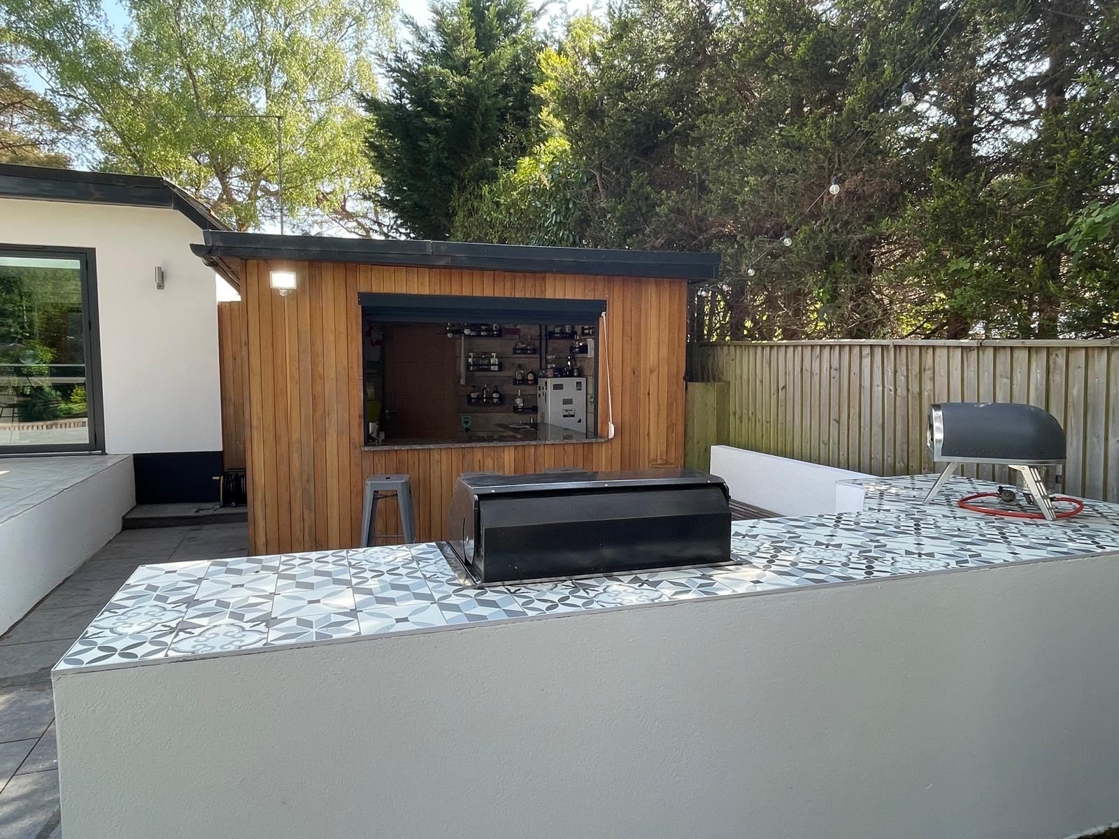 Outdoor kitchen with BBQ and pizza oven in front of the garden bar